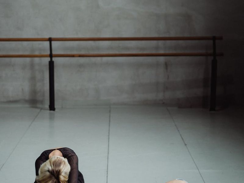 Person performing a stretching exercise in a dark studio